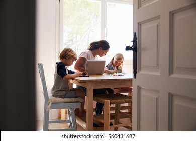 Mum And Two Kids Working In Kitchen, Close Up From Doorway