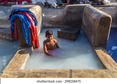 MUMBAI, INDIA - 10 JANUARY 2015: Indian Child Bathes In Traditional Laundromat Pool In Dhobi Ghat. A Well Known Open Air Laundromat In Mumbai.