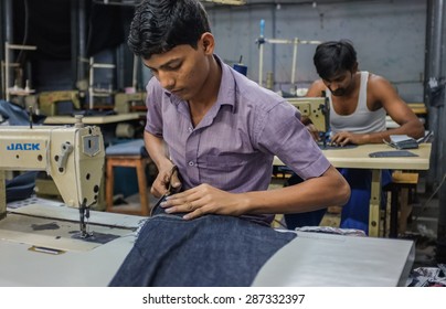 MUMBAI, INDIA - 12 JANUARY 2015: Indian Workers Sewing In A Clothing Factory In Dharavi Slum