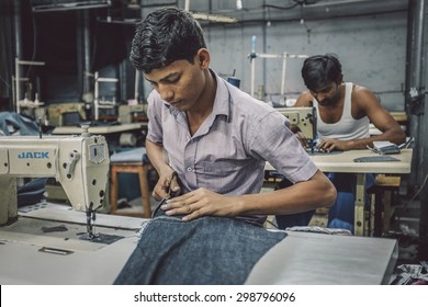 MUMBAI, INDIA - 12 JANUARY 2015: Indian Workers Sew In Clothing Factory In Dharavi Slum. Post-processed With Grain, Texture And Colour Effect.