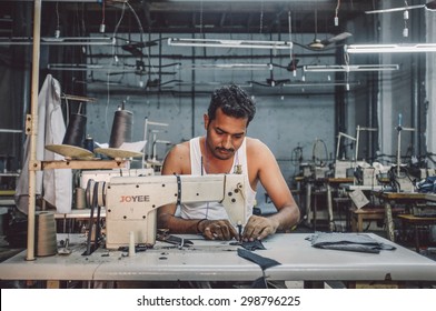 MUMBAI, INDIA - 12 JANUARY 2015: Indian Worker Sews In Clothing Factory In Dharavi Slum. Post-processed With Grain, Texture And Colour Effect.