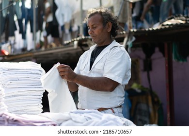 Mumbai, India - 14 February 2022, Man Folding Clothes In World Famous Dhobi Ghat. Indian Labour, Worker, Labor, Poor, Hard Working. Skill India. Jobs, Migrant, Poverty, Wages, Clothes, Wash, Clean.