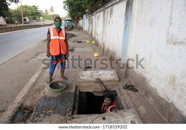 Mumbai / India 30 April 2020 Manhole Worker (Sewer\
workers ) works in the manhole by a team of man and woman in Mumbai\
Maharashtra India