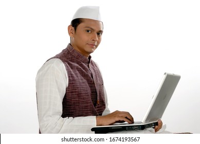 Mumbai; Maharashtra; India- Asia; Dec. 26, 2009 - Portrait of young handsome smiling Indian politician working with laptop white background