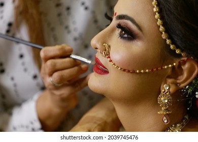 Mumbai Maharashtra India July 06 2019 Selective focus wedding makeup artist making a makeup for bride Beautiful Indian bride getting ready Close-up of face Bridal makeup