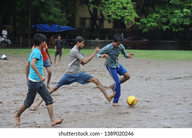 Mumbai; Maharashtra; India -Oct,2013 :  Indian Young Boys Playing Football During Monsoon In Garden