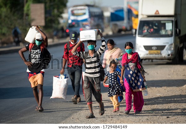MUMBAI/INDIA - MAY 11, 2020: Migrant workers walk on the highway on their journey back home during a nationwide lockdown to fight the spread of the COVID-19 coronavirus.