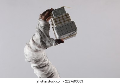 Mummy hand holding gift boxes isolated on gray background. Halloween concept - Powered by Shutterstock