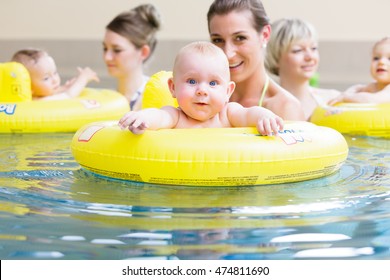 Mums and their children having fun together playing with toys at baby swimming lesson