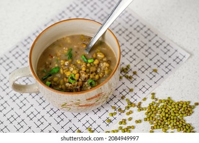 Mungo beans soup in bowl with spoon, dry mungo seed (vigna radiata) on table.