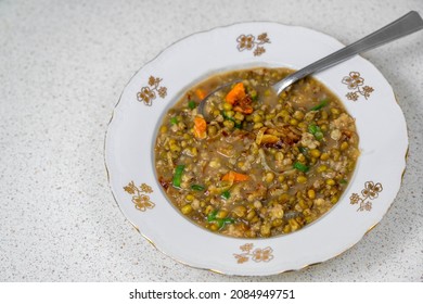 Mungo beans soup (vigna radiata) in plate with spoon (vigna radiata) on table. Vegetarian or vegan food.