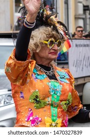 MUNICH, BAVARIA / GERMANY - JULY 13, 2019: A An Older Woman In An Ornage Costume Attending The Gay Pride Parade Also Known As Christopher Street Day (CSD) In Munich, Germany. 