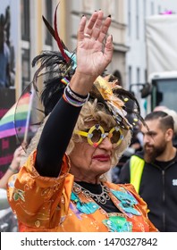 MUNICH, BAVARIA / GERMANY - JULY 13, 2019: A An Older Woman In An Ornage Costume Attending The Gay Pride Parade Also Known As Christopher Street Day (CSD) In Munich, Germany. 