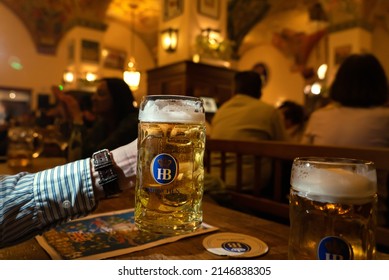 Munich, Germany - 04.07.2022: Famous Hofbräuhaus Traditional Pud Keller In Munich Man Holding HB Beer Jug Krügel