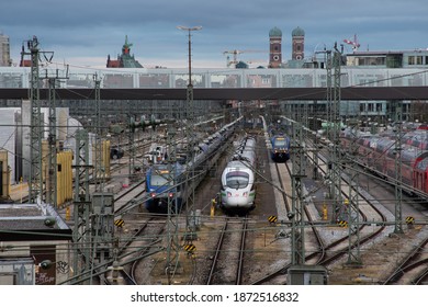 Munich, Germany - December 7, 2020: Trains near Donnersbergerbrücke. The towers of the Frauenkirche cathedral, a Munich landmark, can be seen in the background.