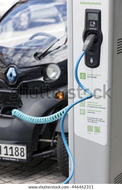 Munich, Germany- June 25, 2016: Electric car,\
Renault, being recharged at plug-in station in front of modern\
office building.