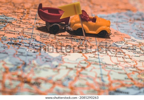 Munich, Germany pinned on map with\
yellow flag and car with boat next to it illustrating road trip to\
camping area or other vacation travel adventures in Europe.\

