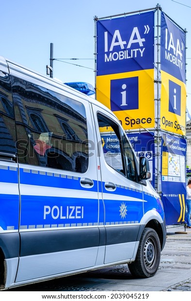 Munich, Germany - September 9: sign of the IAA\
(Internationale Auto Ausstellung - translation: international auto\
exhibition) trade fair and a police car in Munich on September 9,\
2021