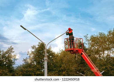 Municipal Worker Man With Helmet And Safety Protective Equipment Installs New Diode Lights. Worker In Lift Bucket Repair Street Light Pole. Modernization Of Street Lamps. Technician On Aerial Device