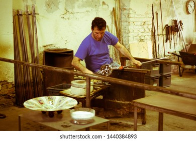 Murano Island, Italy - April 23, 2017: Glassblowing Artisan At Work In A Crystal Glass Workshop In Murano, Venice. Glassmakers Use The Same Tools As Their Ancestors Have Thousands Of Years Ago.