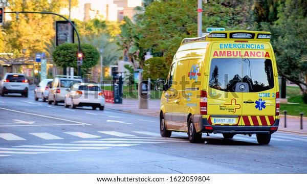 Murcia, Spain,\
January 20, 2019: Yellow ambulance van on a hurry in Murcia city\
about to skip a red traffic\
light