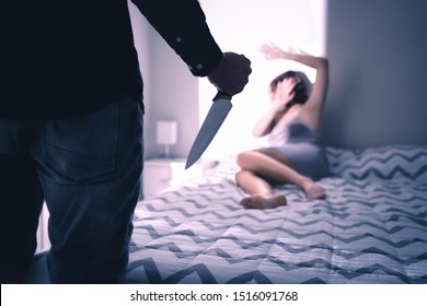 Murder, homicide or halloween concept. Murderer and killer with a knife. Scared woman at home with fear. Scary horror or thriller movie mood or nightmare at night. Victim afraid of psychopath man.