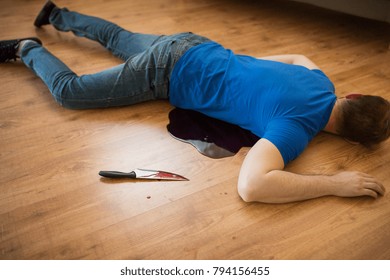 Murder, Kill And People Concept - Dead Man Body And Knife In Blood Lying On Floor At Crime Scene (staged Photo)