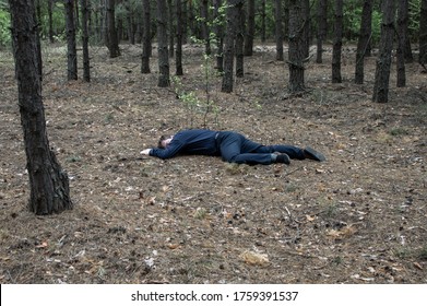 Murder in the woods. The body of a man in a blue shirt and trousers lies on the ground among the trees in the forest. Victim of an attack. Horizontal photo. - Shutterstock ID 1759391537