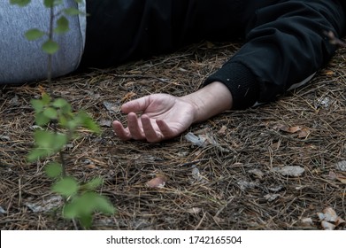 Murder In The Woods. The Hand Of A Dead Woman In A Tracksuit Lies In The Forest On The Ground. The Concept Of Violence Against Women. Horizontal Photo. Close Up.