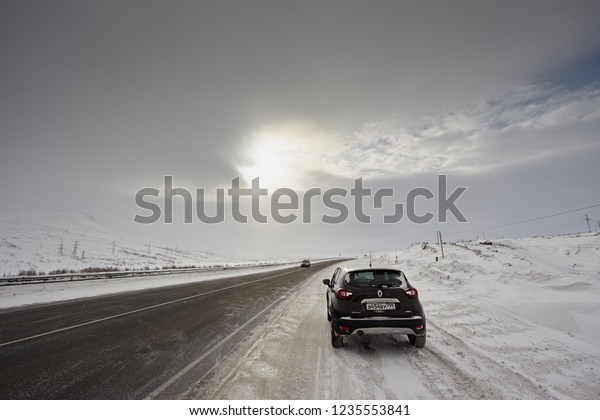Murmansk Region, Russia - March 2018: Renault\
Captur car class suv on a snowy road in winter, against the\
backdrop of a misty sky and the sun. Northern driving conditions\
are very dangerous