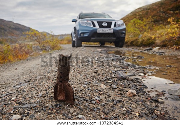 Murmansk region, Russia - September
2017:  Car Nissan Terrano on a rocky road in the mountains, rusty
bomb residue. Dangerous way since the Great Patriotic
War.