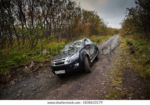 Murmansk region, Russia - September 2018:  Car\
pickup Isuzu D-max rides on a rocky road off-road against the\
backdrop of autumn forests and overcast cloudy overcast skies.\
Dangerous and extreme\
travel