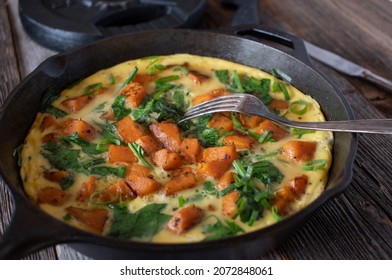 Muscle Building Fitness Meal With A Omelette Cooked With Sweet Potatoes And Spinach. Served With Chives In A Rustic Pan On Wooden Table With Weight Plate In The Background.