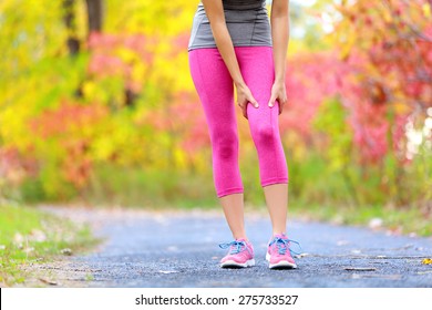 Muscle Injury Of Female Sports Runner Thigh. Woman Running Muscle Strain Injury In Thigh. Closeup Of Runner Touching Leg In Muscle Pain Outside In Fall Forest.