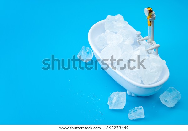 Muscle recovery and healing therapy, performance\
improvement treatment and extreme cold cryotherapy concept with\
minimalist bathtub filled with ice isolated on blue background with\
copy space