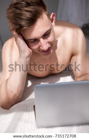 Muscled man have online chatting with girl on bed. Sunny romantic morning at home.
