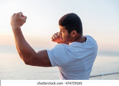 Muscular african american young man athlete standing and practicing shadow boxing outdoors - Powered by Shutterstock