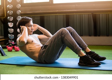 Muscular Asian Man Exercising Doing Sit Up Exercise. Athlete With Six Pack, White Male, No Shirt