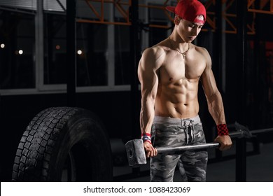 Muscular Asian Man With Sledge Hammer Near Big Wheel Tires In Gym. Equipment For Crossfit Training