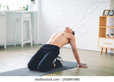 Muscular Asian young man doing  exercises on floor at home