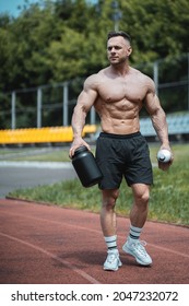 Muscular Athlete Holding Protein Whey Drink In Black Container Or Shaker Outdoor