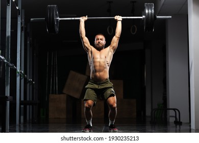 Muscular athlete lifting very heavy barbell. 