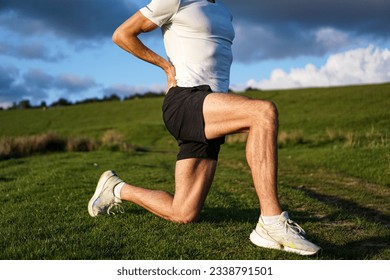 Muscular athlete stretching hamstring and hip flexor in a yoga position on a field during lockdown. Cinematic filter. Runner preparing for a workout session. - Powered by Shutterstock