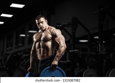 Muscular Athletic Bodybuilder Posing And Exercises In Gym. Sport Power Guy With Big Strong Muscles  And Perfect Body Workout In Gym