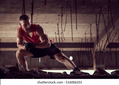 Muscular, athletic built, young man stretching out in a ruin building before workout