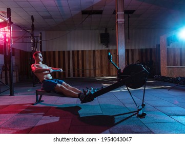 Muscular athletic man exercising in Simulation rowing exercise machine in red blue neon gradient light. Workout in the gym. Strength and endurance training - Powered by Shutterstock