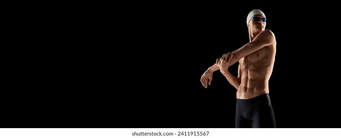 Muscular, athletic young man, swimmer in goggles and cap stretching muscular body before swim over black background.. Banner. Empty space to insert text. Concept of water sport events - Powered by Shutterstock