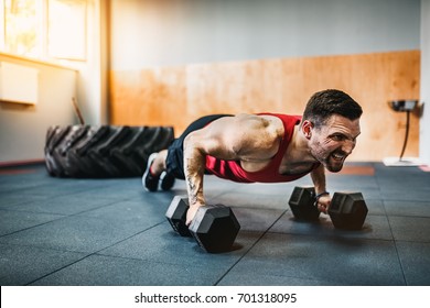 Muscular Bearded Man Doing Push-up Exercise With Dumbbell In A Crossfit Workout