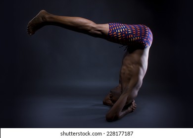 Muscular Black Man Doing Upside Down Yoga On Grey Background