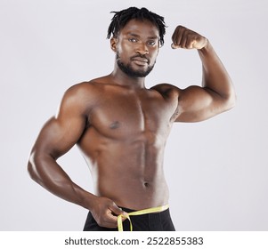 Muscular black man, tape measure and isolated flexing on a grey background for fitness, weight loss or dieting. Portrait of African American male muscle flex, healthy body or empowerment - Powered by Shutterstock